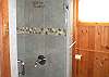 This beautifully tiled shower with glass door has a rain shower head for an exhilarating shower experience.
