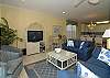 Living room with flat screen TV. The sliding doors open to the back porch that overlooks the pool and ocean.