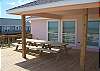 Two large picnic tables on front porch with one large one underneath house.