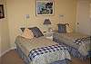 The third bedroom has twin beds, an inside sitting area, adjoining private bathroom access, and opens to a backyard outdoor patio.