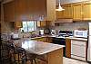 The updated kitchen has granite bar countertops with tile backsplash, next to the great room/dining room area.  All necessary furnishings and cooking utensils are provided, with a gas stove/oven.