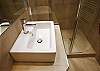 In the bathroom, you have an extra large mirror and lights and an extra large modern shower with a glass door.