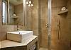 In the bathroom, you have an extra large mirror and lights and an extra large modern shower with a glass door.