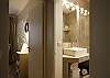 In the bathroom, you have an extra large mirror and lights and an extra large modern shower with a glass door.