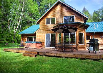 Big backyard with lawn, creek, firepit, decks, gas BBQ and hot tub at Wy'East Log Lodge in Zigzag, Oregon