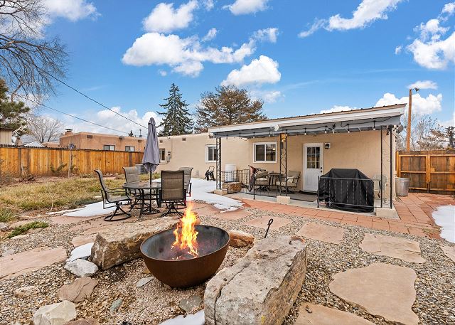Backyard with firepit, grill, and dining table with umbrella