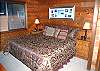 The master bedroom in this home features a king size bed, TV, and a full bathroom.