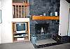 Another view of the living room with a wood fireplace, T.V. and a DVD player.