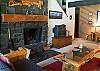 High vaulted ceiling and lots of pine furniture in living room with wood burning fireplace.