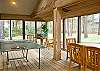 The sunroom has a ping pong table, dining area, and a door to the outside deck.