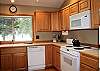Clean and roomy kitchen with a wooded view from the window