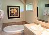 This master bathroom includes a deep jacuzzi tub, tile shower, and double vanity sinks.