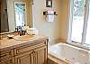 Enjoy this spacious bathroom with a tiled shower and a jacuzzi tub with a view.