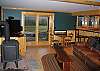 This last photo of the Timber Ridge Retreat Game Room shows the top quality hi-def flat screen TV off to the left, tucked just behind yet by no means obscured by the woodstove.  The sliding glass doors offer immediate access to the luxurious lawn and grand yard that surrounds.