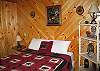 The main floor bedroom of the hand built log home offers a new queen size bed with warm and cozy camp setting comforters.  Hunter's and outdoor enthusiasts will rest easy at "Izzy's".