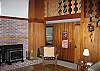 This second view of the Furst Haus living area shows the soap-stone stove and provides just a glimpse of the stairs leading to the 2 upstairs bedrooms matched by a small yet full size bathroom.
