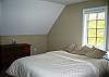The seconds upstairs bedroom in Johnathan's Landing professionally managed vacation rental has a single queen size bed and a great forested view just beyond.  White Mountain pleasures will be await your every morning's awaking.