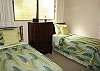 The second bedroom has twin beds and an adjacent bath. It also offers a view out to the garden.
