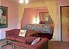 The master bedroom suite with elevated king bed, sitting area, and attached bathroom.