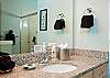 Two Luxurious Bathrooms With Granite Counters and Tile Floors