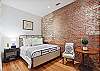 The 4th bedroom features the exposed brick wall and a king sized bed, smart TV and en suite bath.