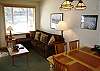 Comfortable living area with fold-out couch, opens onto deck with views of Eagle Run at Mammoth Mountain