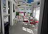 The bright and cheerful sun room features a twin bed and cafe table and chairs. The room overlooks the cottage gardens.