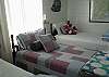 This bright and cheerful bedroom features 3 twin beds. The decor is vintage nautical with red, white and blue bedding, vintage treasures and lots of natural light.  Great bedroom!