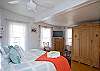 The king bed bedroom features a full bath, which also leads to the outside private shower with hot and cold water and fenced in garden and yard. There is a HD TV with CD/DVD player as well. Bookshelves are filled with books.