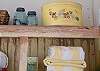 The vintage shelf is filled with an old hat box, blue ball jars with sea shells and little pieces of local art.