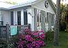 The cottage is surrounded by beautiful flowers, palms and even citrus trees.