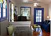 This view from the kitchen looks into the living room which features the tv and  seating. The blue door leads out to the screened porch.