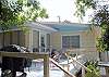This terrific deck is right off the living room and has the charcoal grill, seating  and view of Butler Ave.  The front lot is also part of the property and full of mature , lush palm trees.  The beach is only an eay 5 minute walk from the cottage thru the lot and across Butler Ave. Either the 12th street or 11th Street beach access is yours. The yard is NOT fenced in.