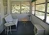 The front of the cottage has an enclosed front porch with screens and windows.  The room faces the east so the morning sun makes this the perfect spot to enjoy your cup of Mermaid Morning Bliss coffee.  We've added pillows to the vintage glider.