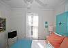 Another view of queen bedroom; flat screen TV; bright cottage white with aqua/coral decor.