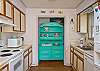 View of kitchen from dining area.  Great aqua china cabinet; this cottage is full of fun color!