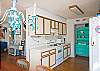 View of kitchen from dining area.  Great aqua china cabinet; this cottage is full of fun color!