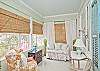 The room is full of wicker, comfy chairs, vintage trunks from the 1940's and shell wreaths. Bamboo blinds and linen curtains cover the windows