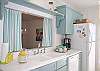 Another view of the kitchen with the pass-through open "window" to the dining area.  Adorable aqua/white striped curtains.
