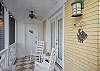The front screened porch features rocking chairs and a view of 7th Street.