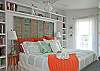 The king bed bedroom features a full bath, which also leads to the outside private shower with hot and cold water and fenced in garden and yard. There is a HD TV with CD/DVD player as well. Bookshelves are filled with books.