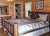The Main Floor Bedroom has a King Size Log Bed with access to the Hot Tub deck with adjoing full bath and walk-in closet.
