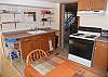 In-law apartment kitchen with electric range, frig, sink and table for two.