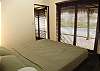 Master Bedroom with King bed, TV/DVD, ensuite bathroom and closet, overlooking the pool through a sliding door with blinds at Casa Gris vacation rental home in Jaco, Costa Rica