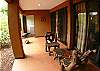 Back covered terrace with rustic chairs and table, charcoal grill and laundry with washer and dryer at La Flor Rustico beachfront vacation rental in Jaco, Costa Rica