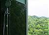 Shower with large floor to ceiling window with view of the rainforest, finished in marble and boasting two shower heads, within the Master Bathroom at Casa Infinito luxury vacation rental home at Valle Perdido in Playa Hermosa, Costa Rica