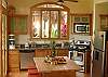 Full kitchen with stainless steel appliances, including dishwasher, and working island with wood top and stools, at Villa Oceana vacation rental home in Esterillos, Costa Rica, half way between Jaco and Manuel Antonio.