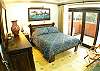 Second bedroom with wooden Queen bed, closet and chest of drawers, as well as balcony, at La Flor del Paraiso vacation rental home in Jaco's only beachfront single-family home gated community.