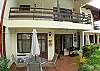 Townhouse seen from pool area at Rio Copey vacation rental in Jaco beach.  Terrace has table with umbrella and charcoal grill.  There are 2 pool lounge chairs too.