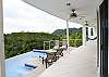 Long tiled terrace that follows the design of the pool, with sliding glass doors with screens at Casa Infinito luxury vacation rental home at Valle Perdido in Playa Hermosa, Costa Rica